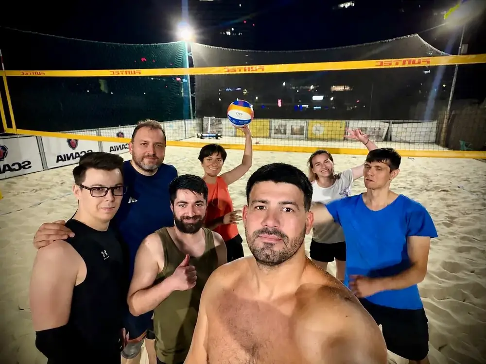 Grup de prieteni pe terenul de volei pe nisip, seara