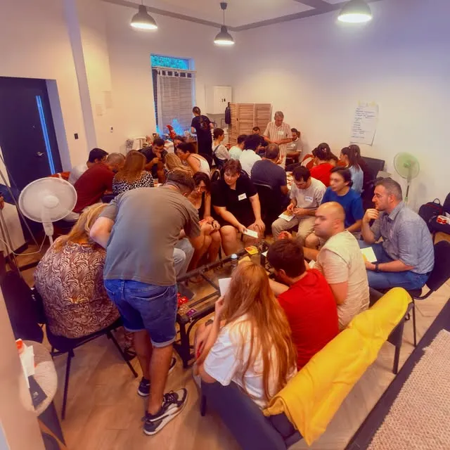 Întâlnire numeroasă a comunității Gatherings într-un spațiu cu mese comune