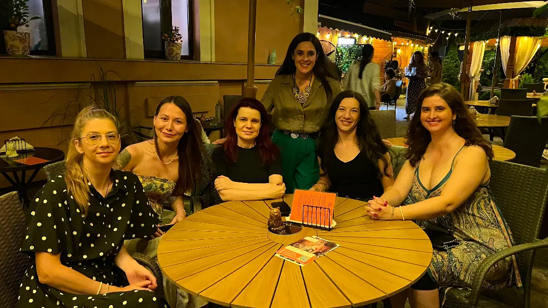 Grup de participante la o discuție în jurul unei mese, într-un cafeneu din București